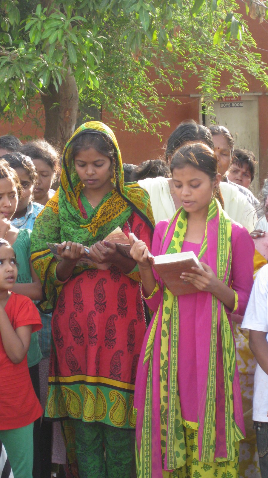 Young women reading passages from the Bhagavad Gita, Quran, and Bible.