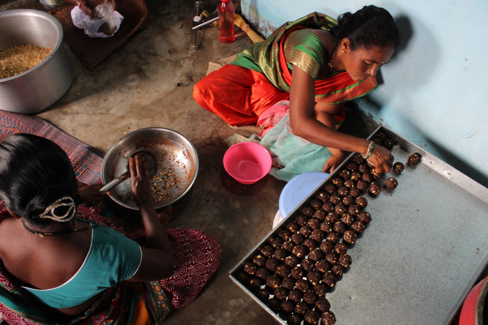 SHG women making ladu sweets for school distribution.