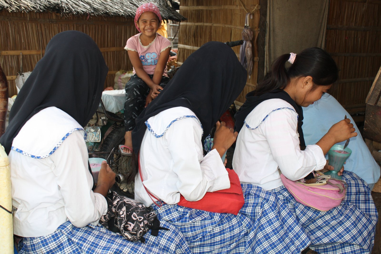 High school girls in their school uniforms take a break at  a food stall at an evacuation camp for internally displaced persons in Maguindanao, Philippines. Behind them is the stall owner's daughter, who is in grade 3. Photo taken on January 28, 2009 by libudsuroy. Creativecommons.