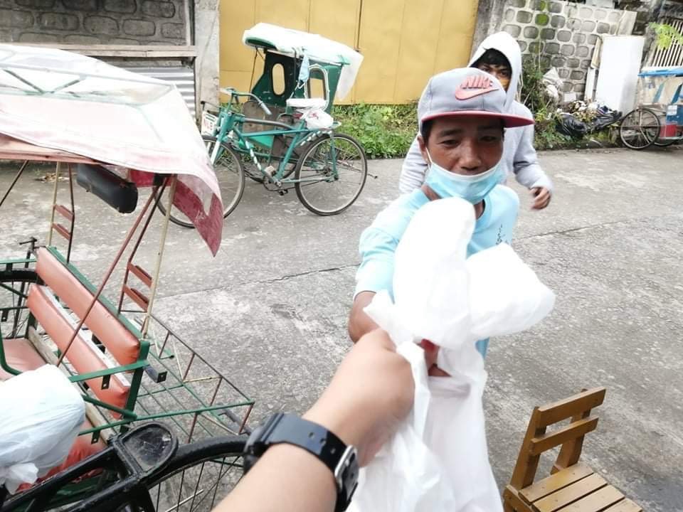 Painter Angel distributes food items to pedicab drivers in her village