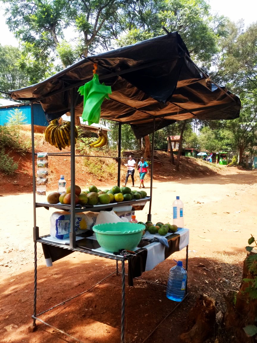 A typical roadside trading kiosk and a source of livelihood for many women on the fringes like my mother. (this one is upmarket, though; overhead shelter and bottled water being a luxury)